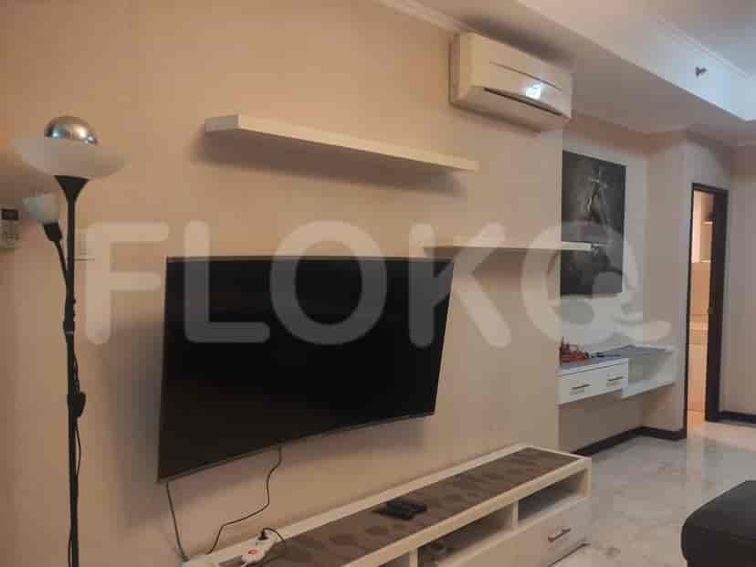 A living room with a smart TV mounted on the wall, white shelves and white side cabinet.
