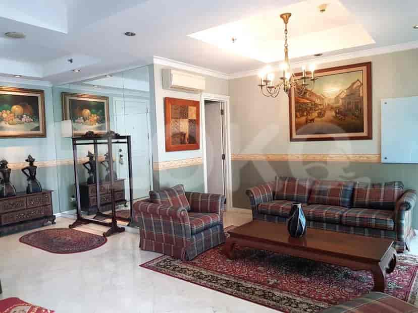 A living area with a plaid sofa, armchair, and artwork, complemented by a patterned rug.
