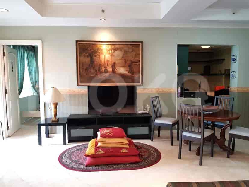 A living room with a TV, dining set, and art.
