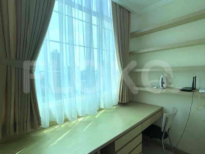 A bedroom with a desk and large window.