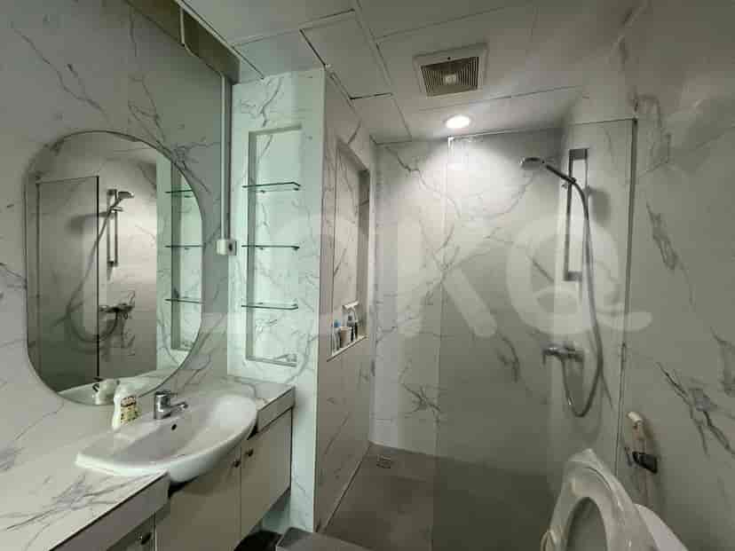 Bathroom with a round mirror, shower, and marble-like tiles.