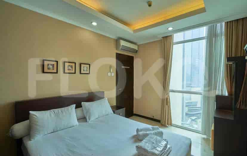 A bedroom with a bed, large window, and side table.
