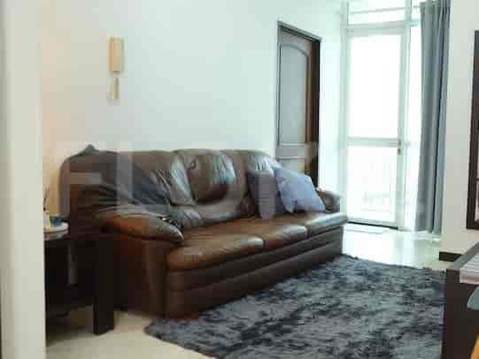 A brown leather sofa in a living room with a dark grey rug.