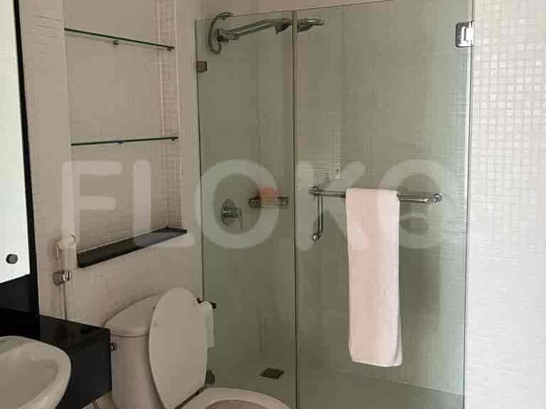 Kamar mandi modern dengan pancuran kaca dan toilet.