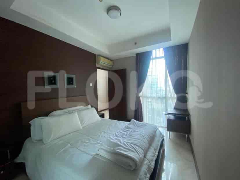 A well-lit bedroom featuring a king-size bed with comfortable bedding and a view of the city.