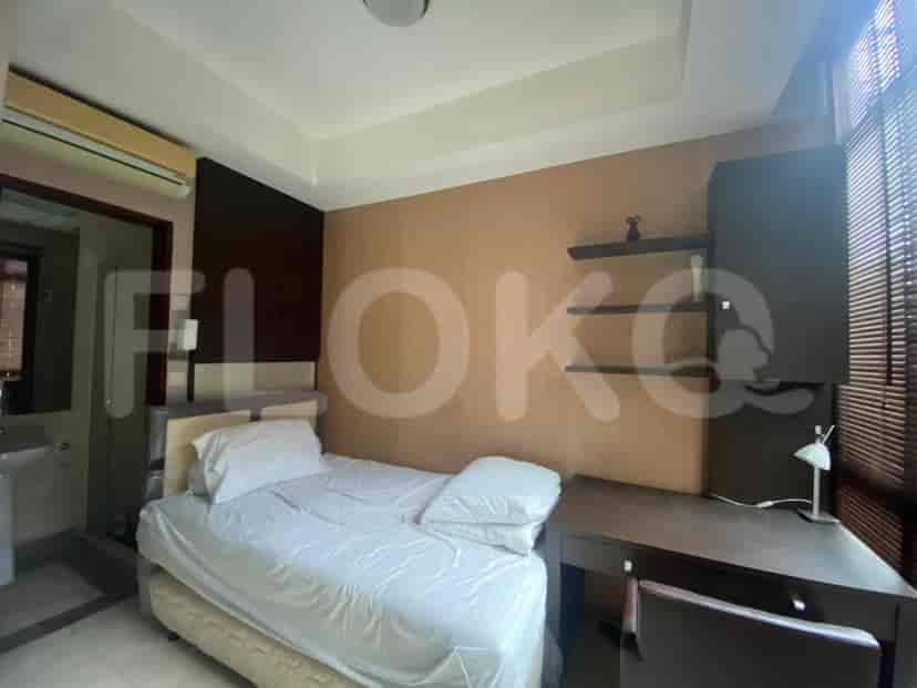A small bedroom with a single bed, a desk, and a wall-mounted air conditioning unit.