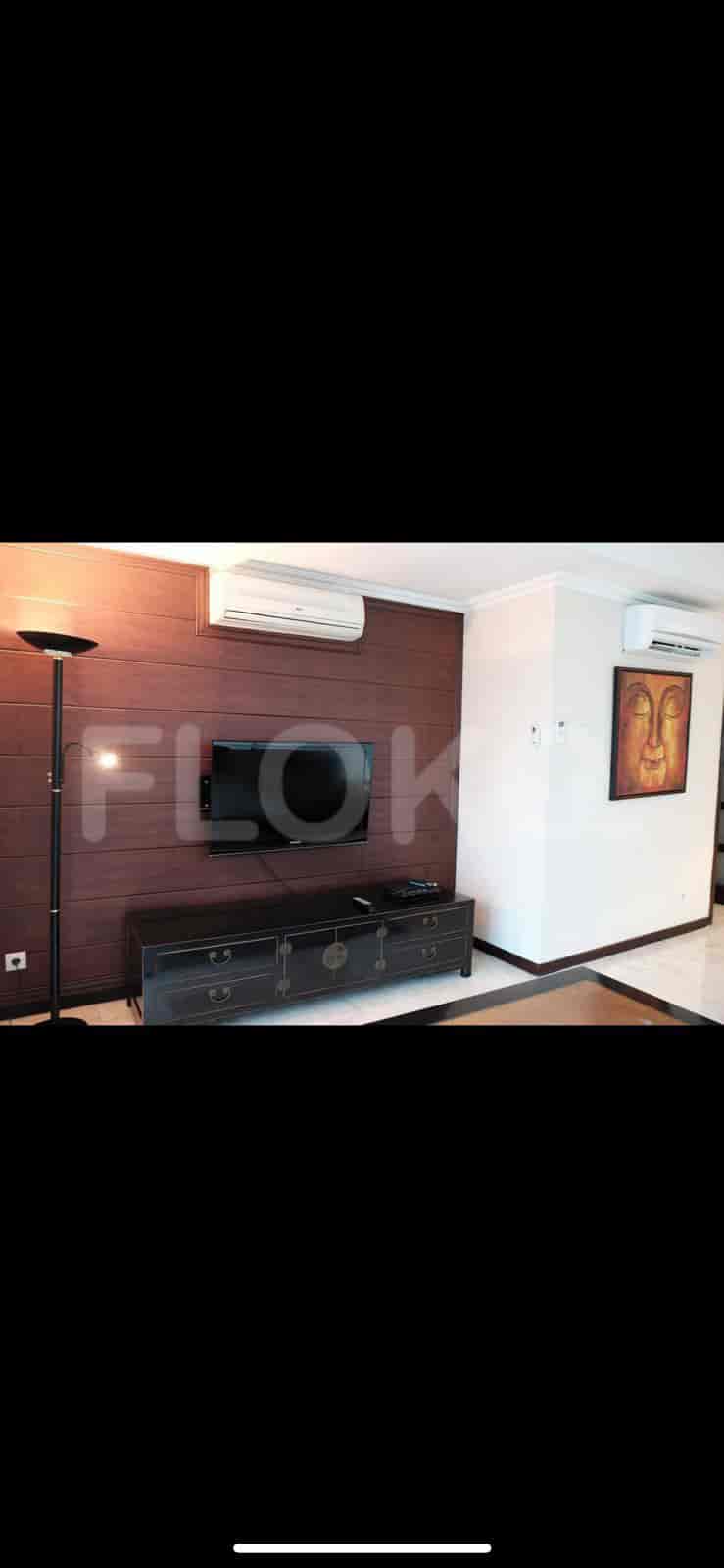 A living room with a TV, wall-mounted AC unit, and dark wood paneling.