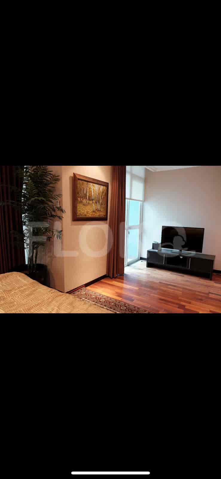 A bedroom with a TV, wooden flooring, and a large painting on the wall.