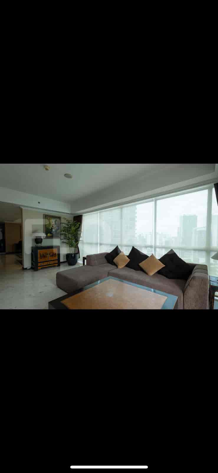 A living room with an L-shaped sofa and a large window with city views.