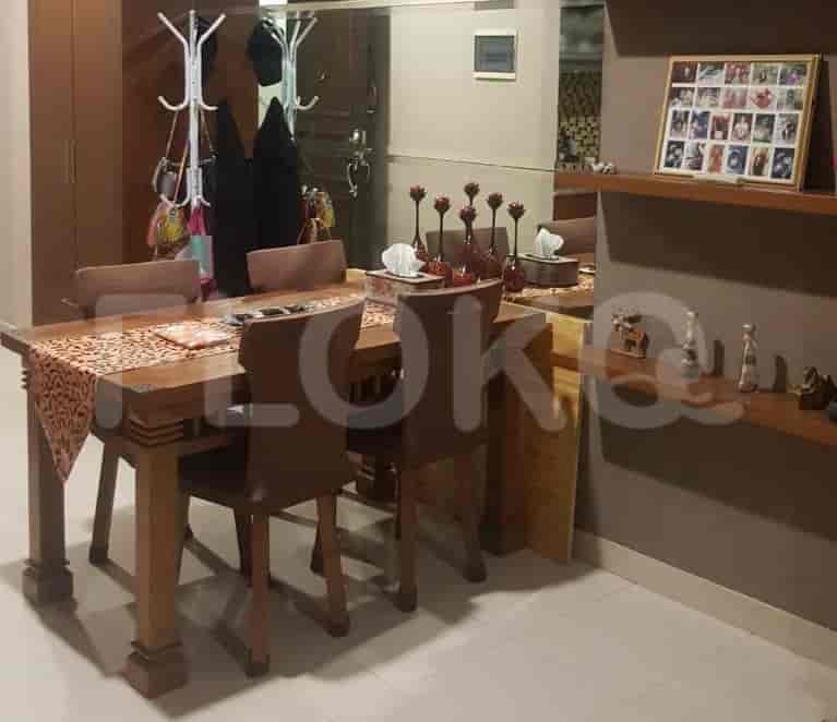 A dining area with a wooden table and six chairs, featuring artwork and a mirror.