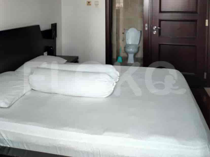 Bedroom with a bed, headboard and bathroom entrance visible.
