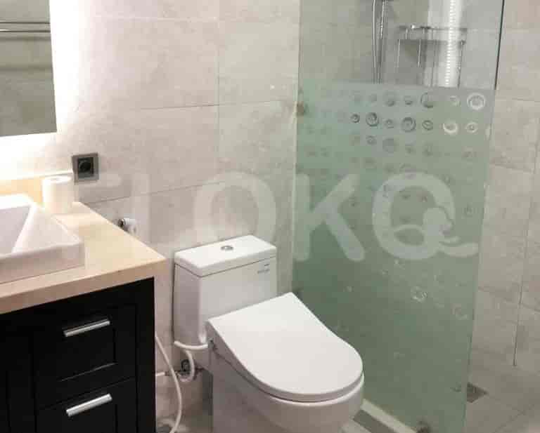 A modern bathroom featuring a toilet and sink, with a glass shower enclosure.