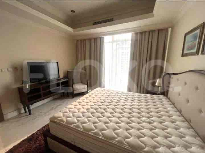 A well-lit bedroom with a bed, tv and neutral color palette.