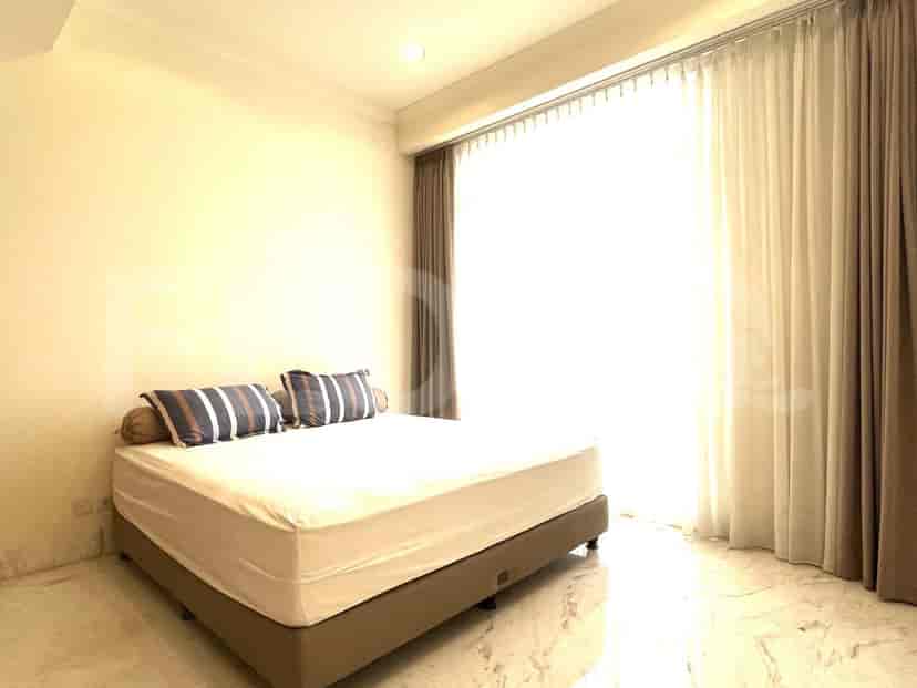 A bedroom with a bed and large windows.