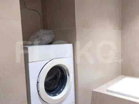 Kamar mandi yang terang dengan mesin cuci, dan dinding ubin.