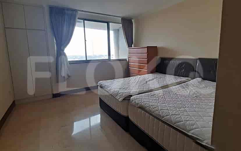 A bedroom with two twin beds, a large window, and a chest of drawers.