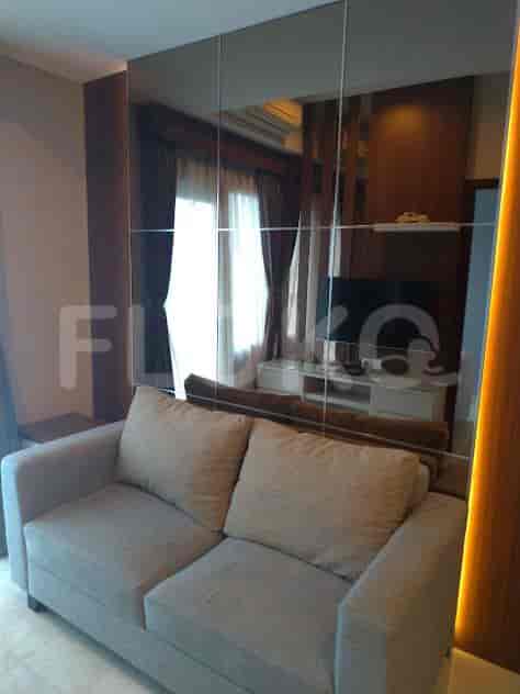 A well-lit living room with a grey sofa, large mirror wall, and a wall-mounted TV.