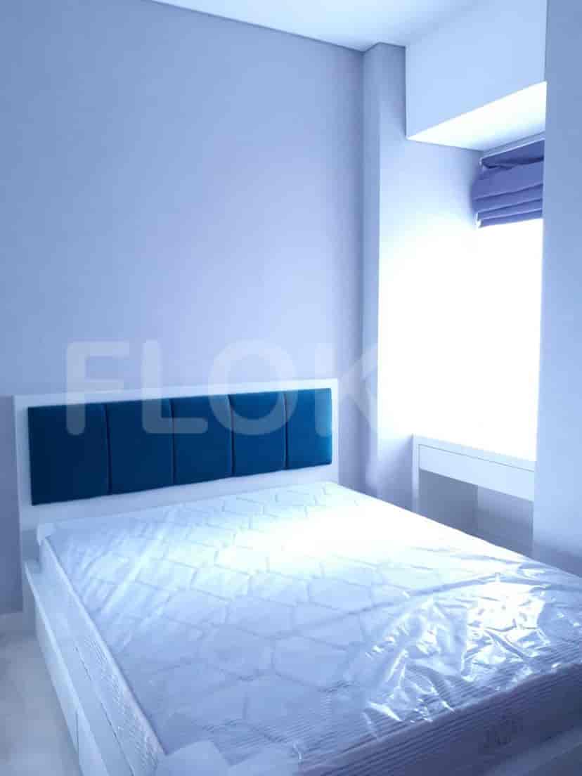 Bedroom with a bed covered in plastic, a blue headboard, and a large window.