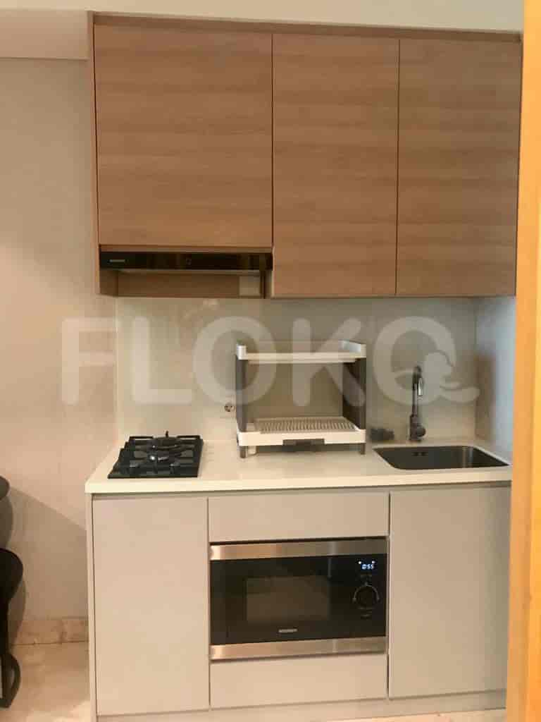A modern, compact kitchen with wooden cabinetry, an electric stove, and a microwave.