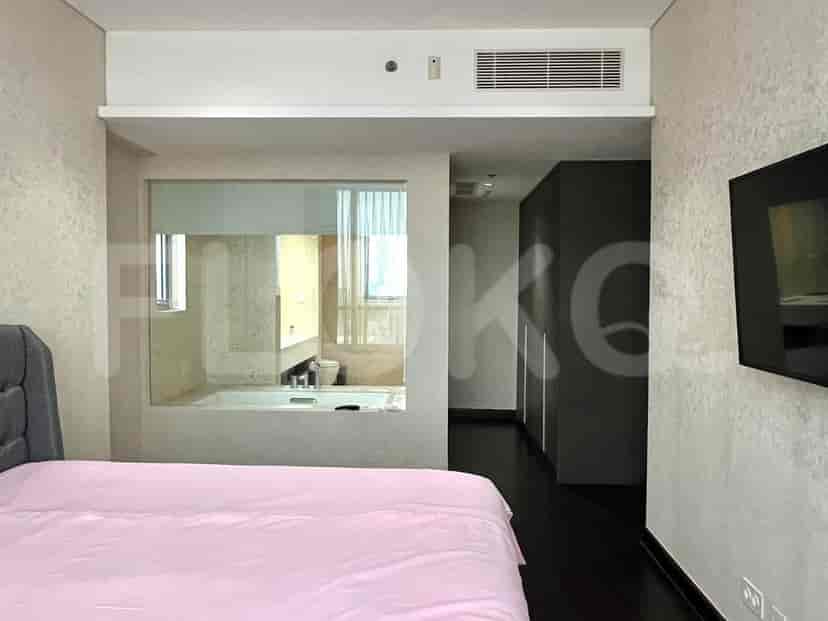 A bedroom with a view of the bathroom, including a bathtub and a large window.