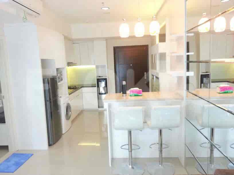 Sebuah dapur modern dengan lemari putih, meja sarapan dengan bangku, dan peralatan stainless steel.