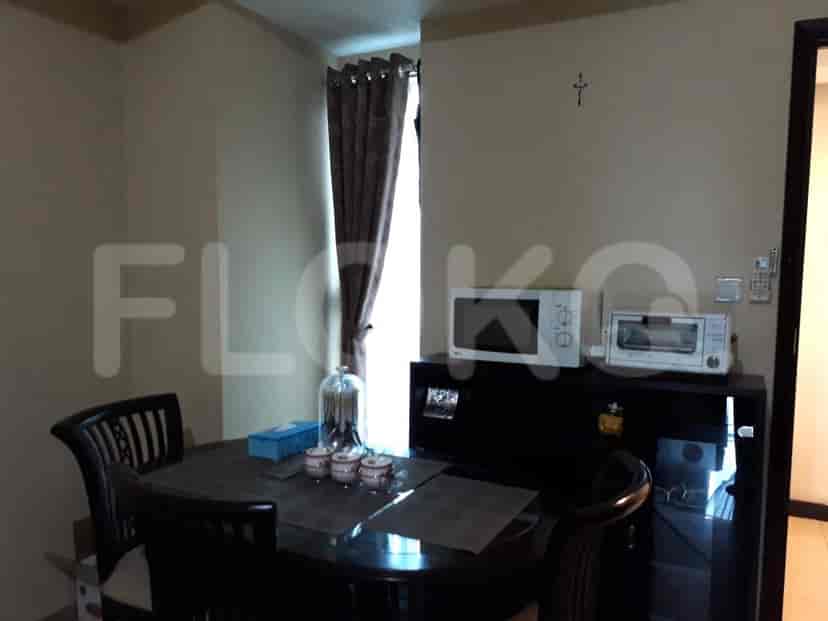 A dining area with a round dark wood table and chairs, a microwave, and a window with curtains.
