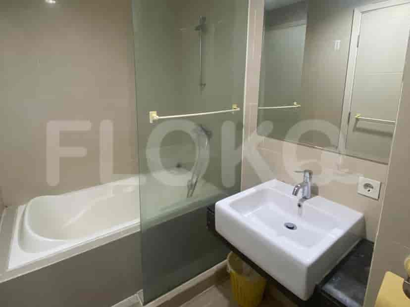 Kamar mandi modern dengan bathtub, shower kaca, dan wastafel.