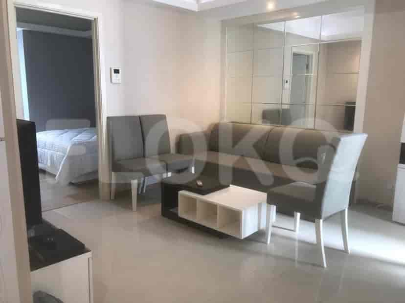 Ruang tamu yang terang benderang dengan sofa, kursi, dan akses ke ruangan lain.