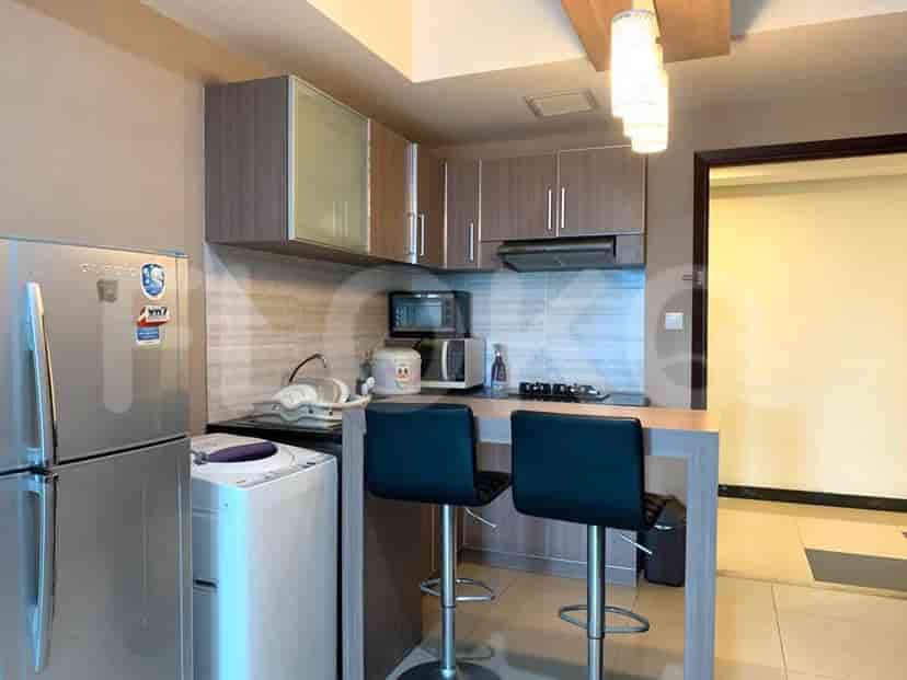 A compact kitchen area with a fridge, washing machine, and breakfast bar.
