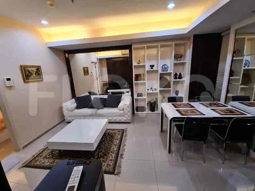Modern living room with white sofa, coffee table, dining area, and built-in shelves.