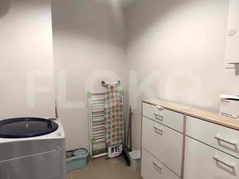 Laundry room with a washing machine, ironing board, and storage.