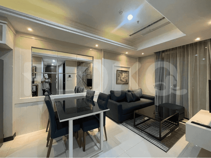 Dining area with a glass top dining table, sofa, and a view into the kitchen.