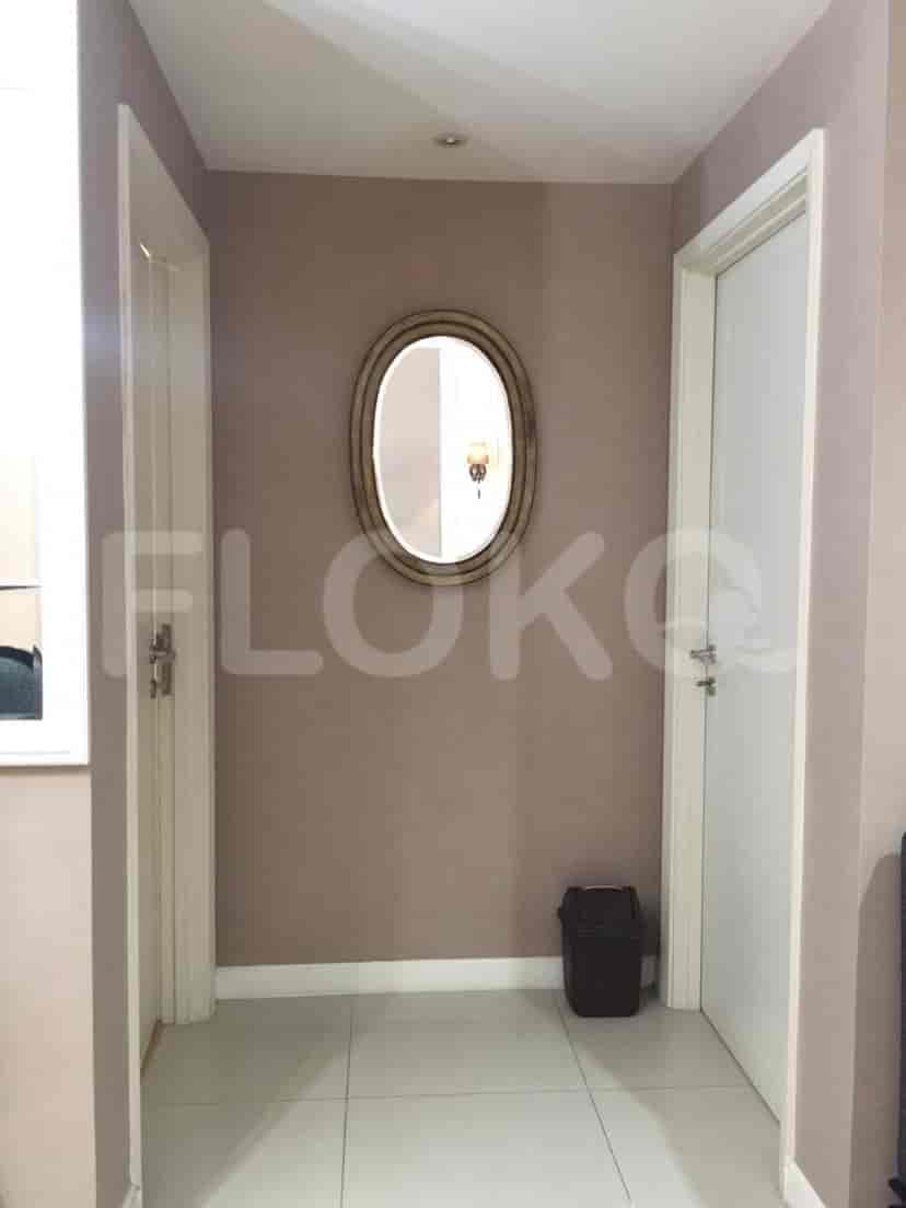 A hallway with white doors, a mirror, and a trash can.