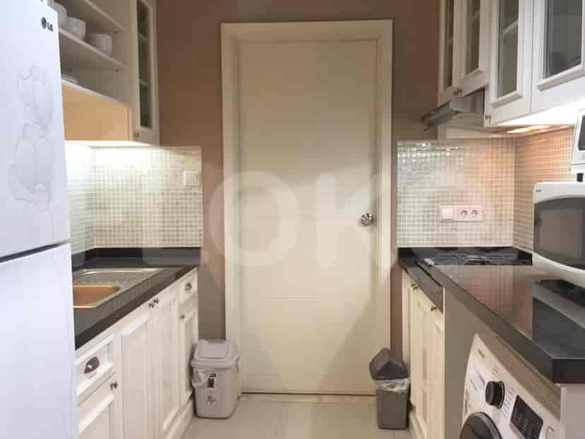 A kitchen with white cabinets, black countertops, and a door.
