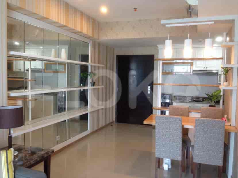 A spacious living and dining area with a mirrored wall, open shelves, and a dining table.