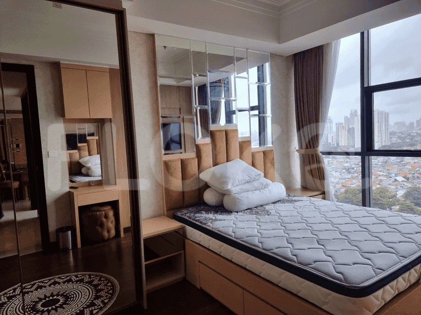 A bedroom with a bed, large mirror, and cityscape views through the window.
