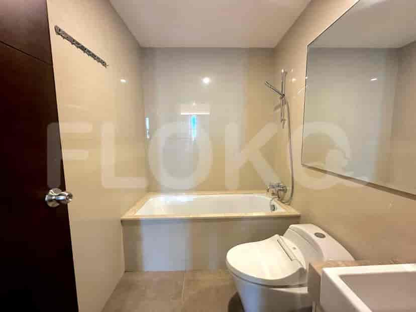 A modern bathroom with a bathtub, toilet, and a large mirror.