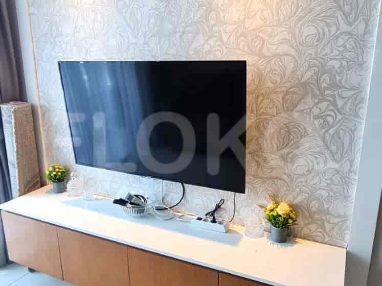 Living area with a TV, wooden storage, and patterned wallpaper.