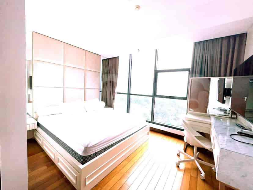 A bedroom with a bed, a vanity, and large windows.