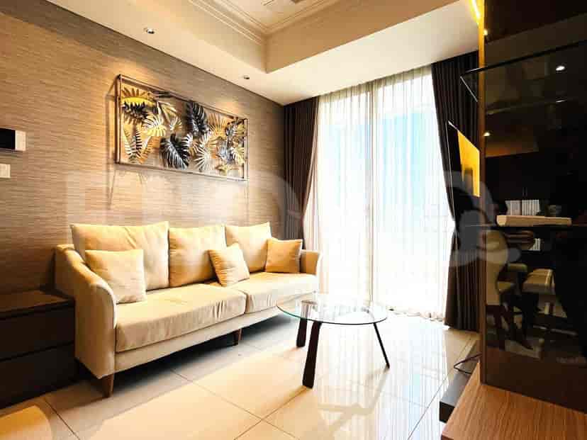 Modern living room with beige sofa, glass coffee table, and decorative wall art.