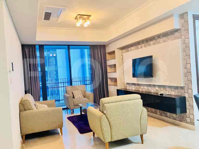 Modern living room with three beige armchairs, a glass table, and a mounted TV.