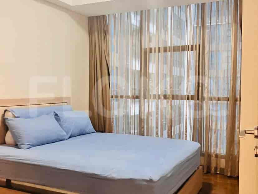 Bedroom with a light-colored bed, soft blue bedding, and sheer curtains.