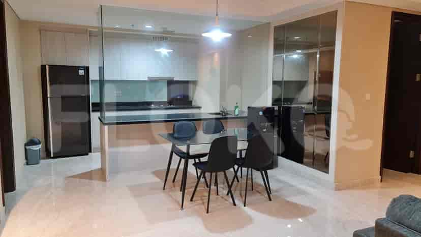 A modern kitchen and dining area, featuring a glass partition, black countertops, and dark dining chairs.