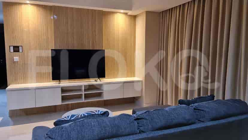 A spacious living room with a built-in TV unit, a large grey sofa, and beige curtains.