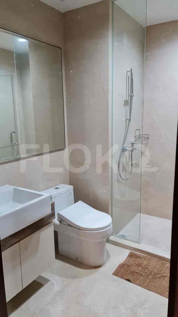 A bathroom with a glass shower enclosure, a vanity, and a toilet.