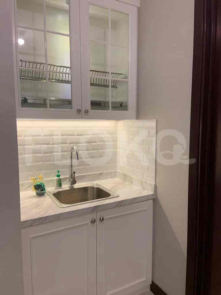 A modern kitchen with white cabinets, marble countertops, and stainless steel sink.
