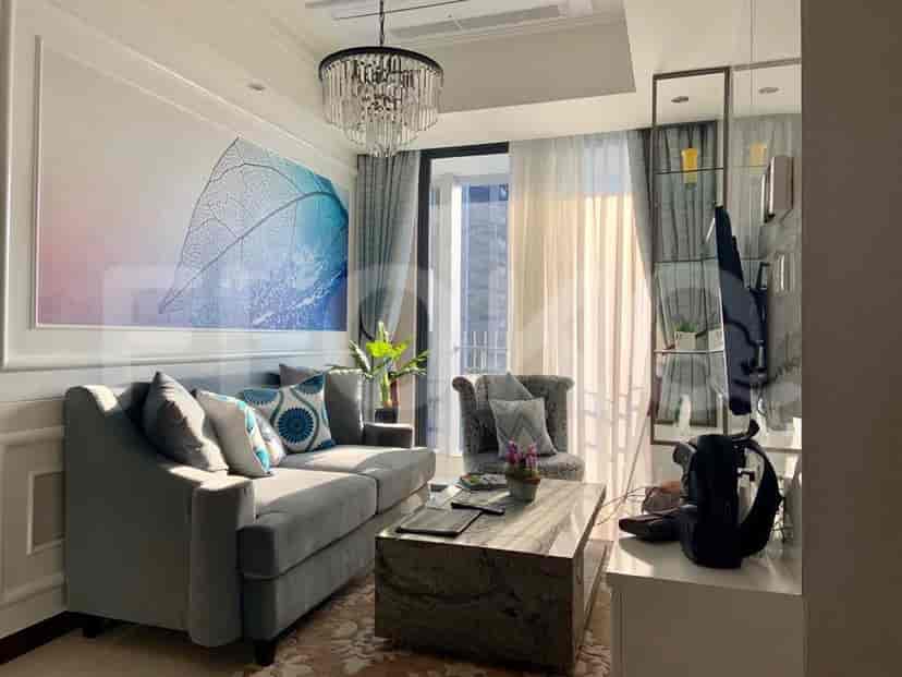A living room with a grey sofa, large artwork, and a chandelier.