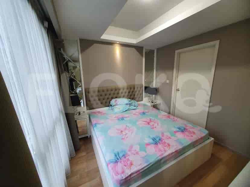 Kamar tidur dengan tempat tidur, meja samping tempat tidur, dan jendela besar.