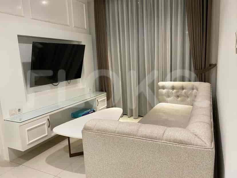 Living room with a TV, sofa and coffee table, next to a window.