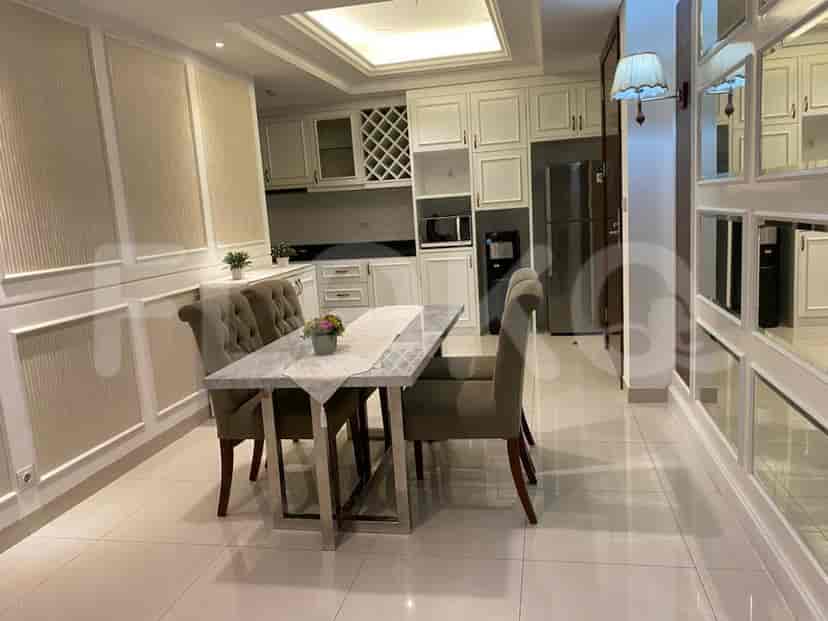 A dining area with a modern table and a kitchen with white cabinets.